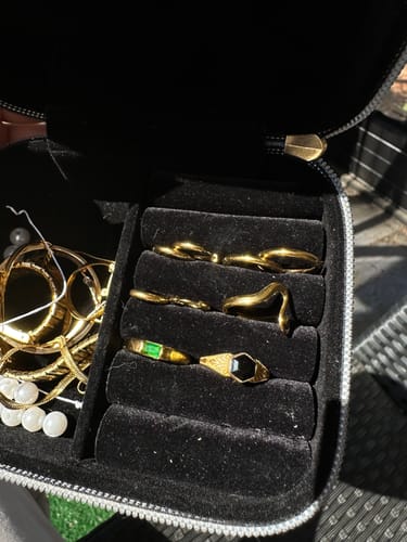 Reviewer's Gold Trio Mini Hoop Set inside an open black jewelry case with other gold jewelry.
