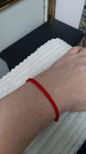 Un client portant le bracelet porte-bonheur 'Tibétain' rouge à son poignet.