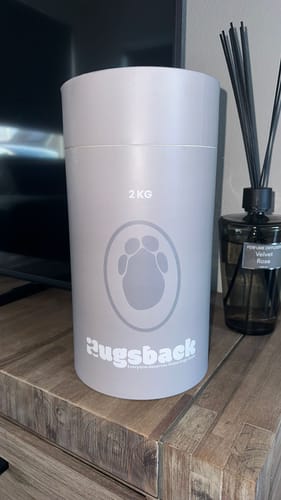 Recensent toont de grijze, cilindrische verpakking van de Olifant verzwaringsknuffel.