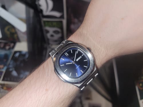 Reviewer wearing a watch with a silver-colored metal band and a blue face.