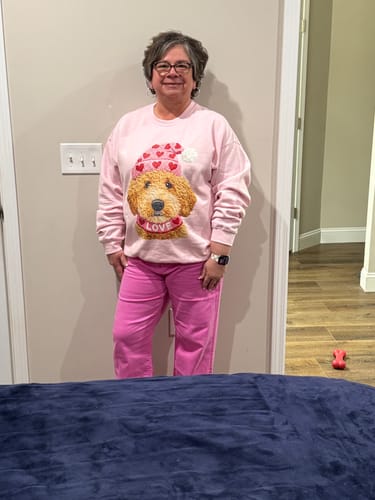 Reviewer standing indoors wearing the pink Dani Denim Jeans with a Valentine's Day sweatshirt.
