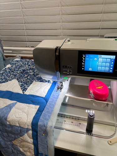 Reviewer using the Sew Steady Sewing Machine Extension Table to sew a blue and white quilt on their machine.