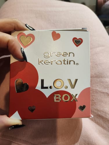 Cliente tenant la L.O.V Box, un élégant coffret blanc et rouge décoré de cœurs dorés.