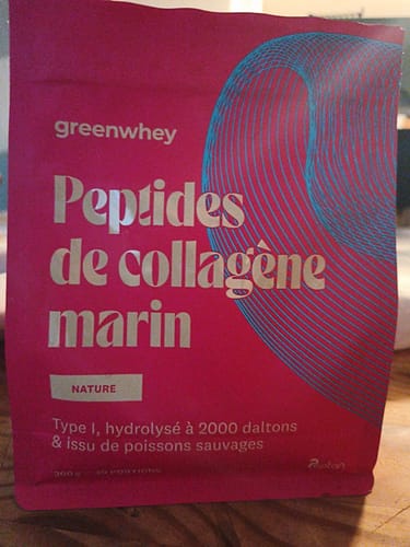 Le sachet rose de Peptides de Collagène Marin d'un client, posé sur une table en bois.