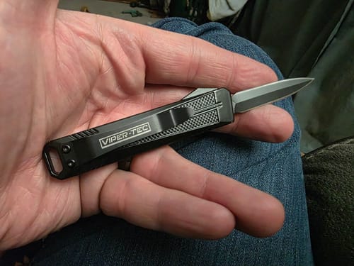 Reviewer holding the compact black VT Mini Stinger OTF Knife in their palm with the blade extended.
