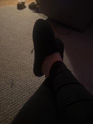 Reviewer wearing the black textured Cloud Slides while relaxing indoors.