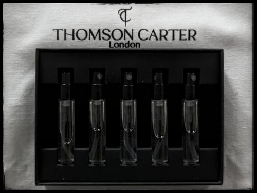 Customer's close-up of the Fragrance Discovery Kit, showing five small vials in a black holder on the branded white pouch.