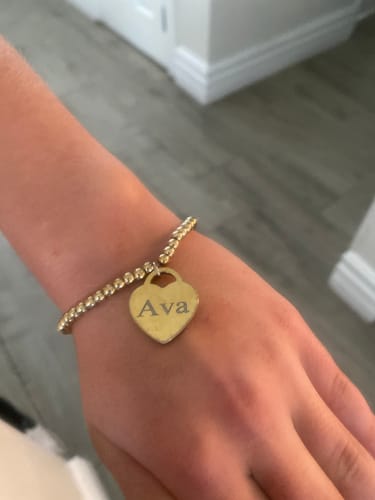 Customer wearing the Heart Stretch Bead Bracelet on their wrist, showing the heart charm engraved with 'Ava'.