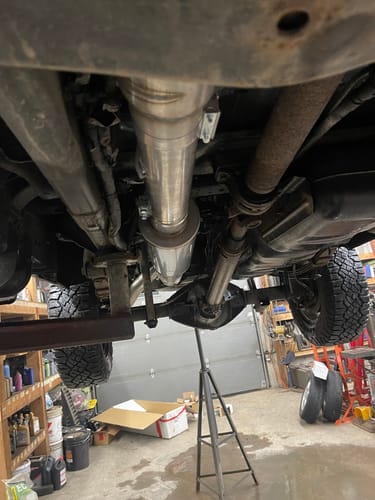 Customer's newly installed Cummins 4" exhaust system with muffler, seen from under the truck on a lift.