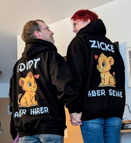 Zwei Rezensenten von hinten in passenden schwarzen 'Idiot Löwe' Hoodies.