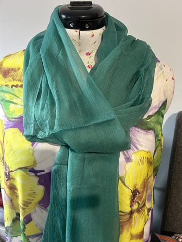 Reviewer's green crepe fabric from the bundle, draped like a scarf around a floral print dress form.