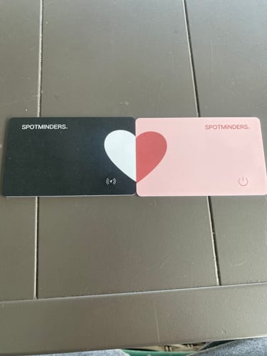 Customer's black and pink SPOTMINDERS. Wireless Chargers arranged to form a heart on a table.