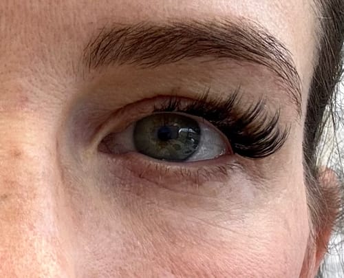 Nahaufnahme des Auges einer Kundin, die die langen, geschwungenen Lovers Lane Wimpern trägt.