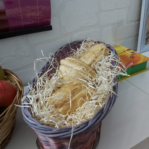 Ein Kunde zeigt drei helle Chayote von Julian, die gut verpackt in einem Korb liegen.