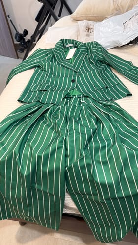 Customer's green and white striped notched collar blazer and matching pants laid out on a bed.