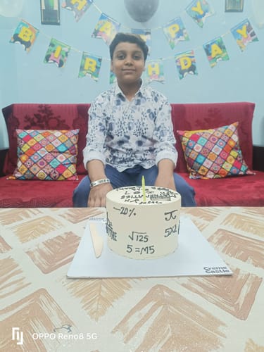 Customer sitting with the Mathematics Theme Birthday Cake on a table. The white cake is decorated with neat math equations.