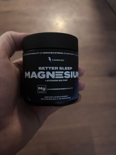 Reviewer holding a black tub of Complex's Better Sleep Magnesium capsules.