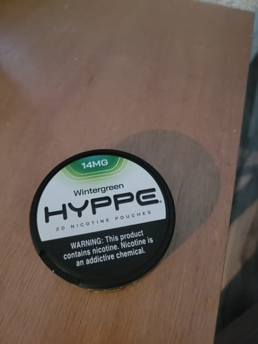 Customer's can of Wintergreen 14mg nicotine pouches resting on a wooden surface.