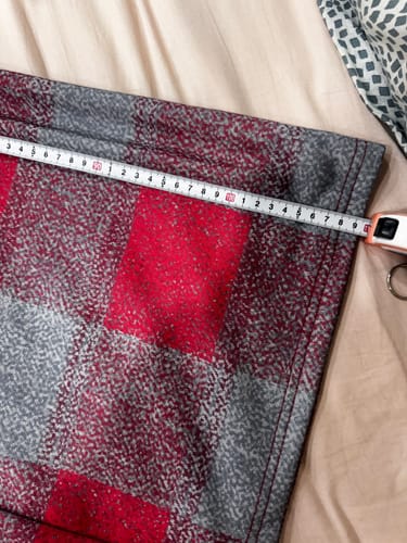 Close-up of a customer measuring the fabric of the red and gray Loose Wide Leg Pants.