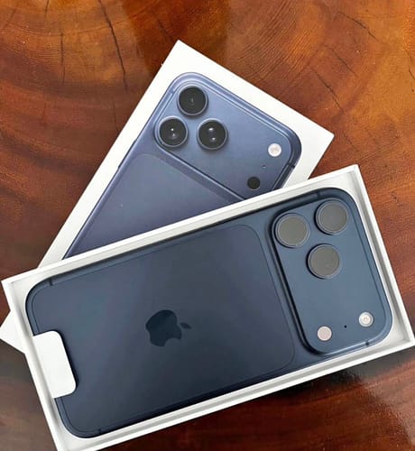 Cliente mostrando su nuevo IPHONE 17 PRO MAX azul oscuro dentro de su caja blanca abierta.