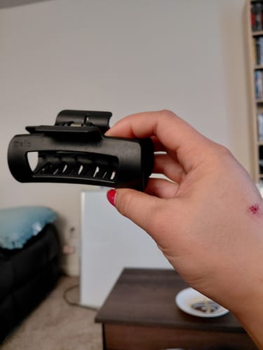 Customer's hand, with a scrape from a car accident, holding the undamaged black cloud clip.