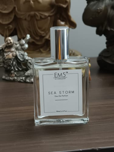 Customer's clear, square bottle of Sea Storm Eau De Parfum with a silver cap on a wooden table.