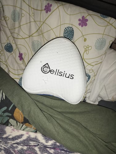 Client montrant son coussin orthopédique Cellsius blanc posé sur un lit.