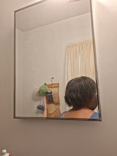 Customer showing the back of their shoulder-length hair in a mirror after using the edge control.