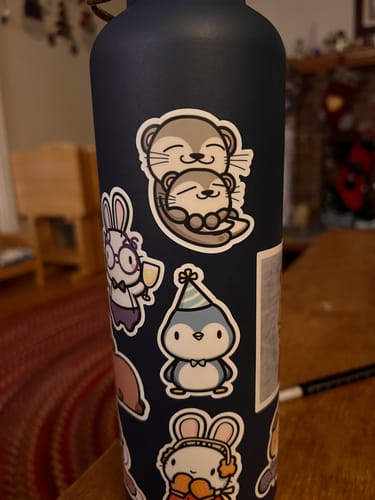 Reviewer's adorable My Otter Half sticker shown on a dark water bottle among other cute stickers.