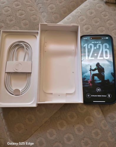Cliente mostrando su nuevo IPHONE 17 PRO MAX encendido junto a su caja abierta y el cable.
