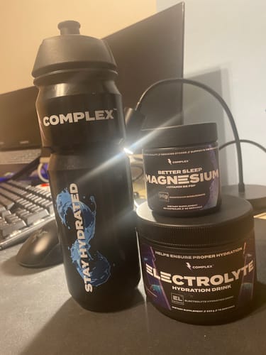 Customer's Sleep Magnesium tub on a desk with the brand's electrolyte drink and a black water bottle.