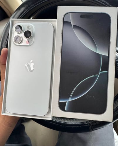 Cliente mostrando su nuevo iPhone Pro Max de color claro dentro de su caja abierta.