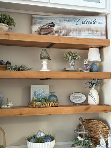 Customer's 'Lose Yourself in Lakeside Bliss' canvas sign displayed on a wooden floating shelf with coastal decor.