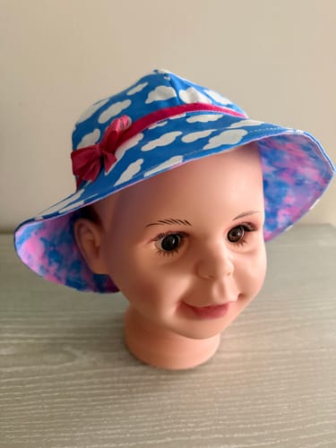 Reviewer's handmade child's hat on a mannequin, with the Fantasy Foggy Clouds fabric visible as the pink and blue inner lining.