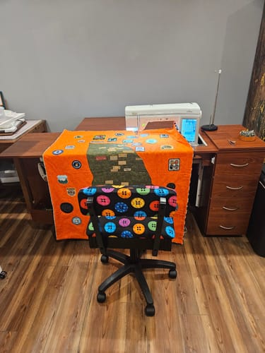 Customer's Arrow Hydraulic Sewing Chair with a colorful button-patterned fabric in a sewing room.