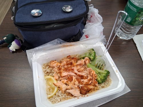 Customer's Lean Lemon Turkey meal served in a white container with brown rice, broccoli, and a lemon wedge.