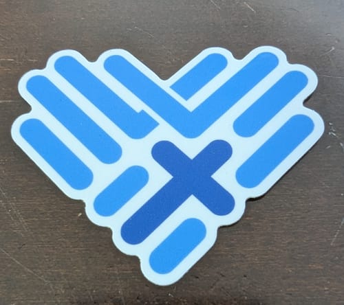 Customer's custom vinyl sticker with a blue, heart-shaped design made of woven lines and a central cross.