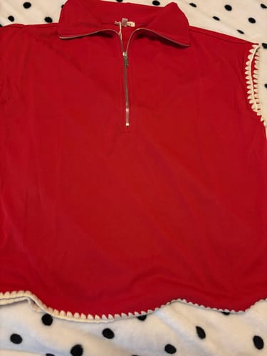 Customer's red quarter-zip tee laid flat, showing the white scalloped stitched trim.