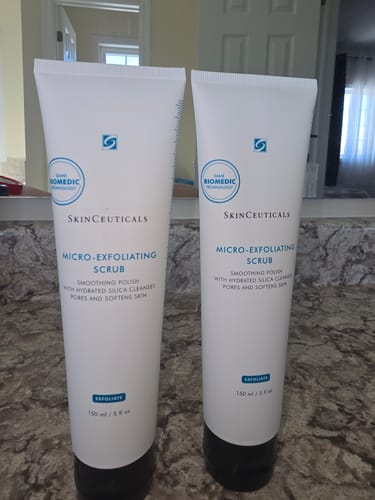 Reviewer's two white tubes of SkinCeuticals Micro-Exfoliating Scrub standing on a bathroom countertop.