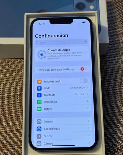El iPhone 13 de un cliente en su caja, con la pantalla mostrando el menú de configuración.
