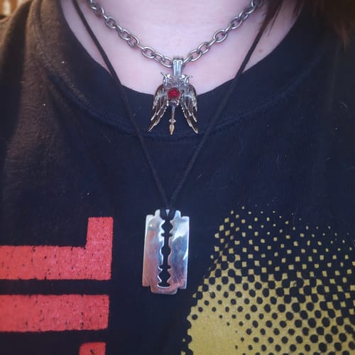 Customer wearing their Aries Zodiac Pendant on a silver chain. The detailed pendant has a central red gem.