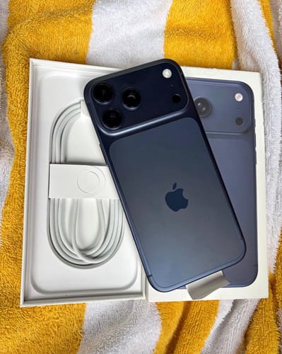 El IPHONE 17 PRO MAX azul de un cliente sobre su caja abierta, mostrando el reverso del teléfono.