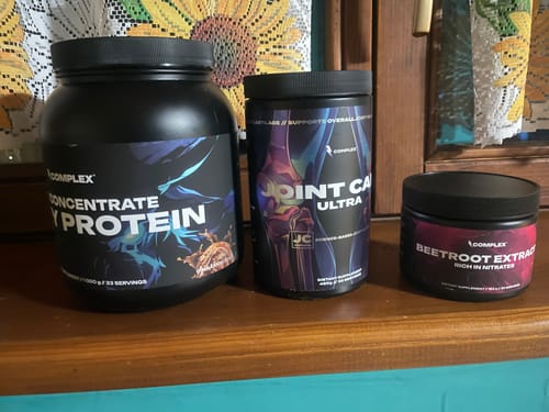 Reviewer's collection of Complex brand supplements, including protein, joint care, and beetroot extract, on a wooden shelf.