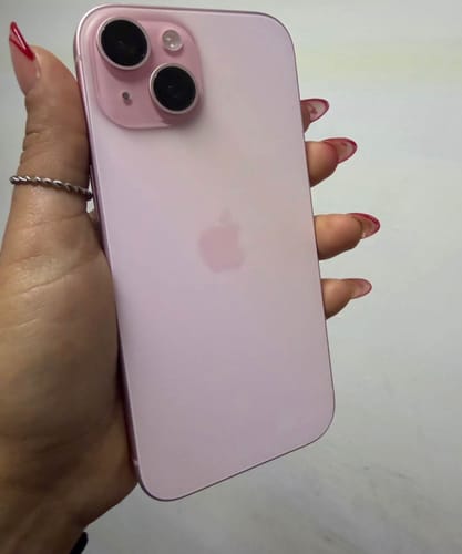 Cliente sosteniendo la parte trasera de un iPhone 15 rosa.