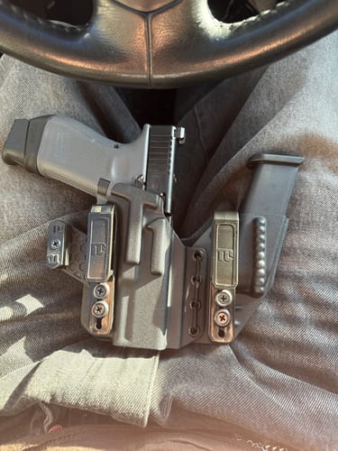Customer's grey AXIS ELITE holster with a firearm and magazine, shown on their lap while sitting in a car.