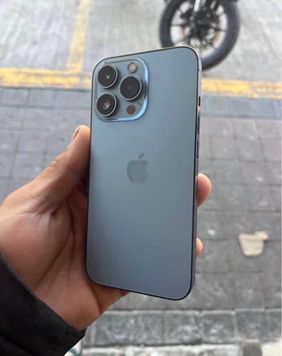 Un cliente sostiene la parte trasera de un iPhone 13 Pro azul en su mano.