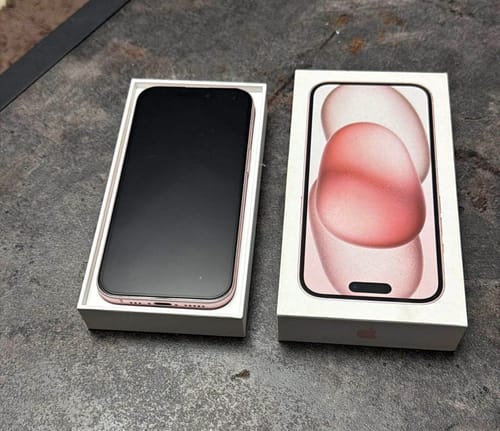 Un cliente muestra su nuevo iPhone 15 rosa recién sacado de la caja.