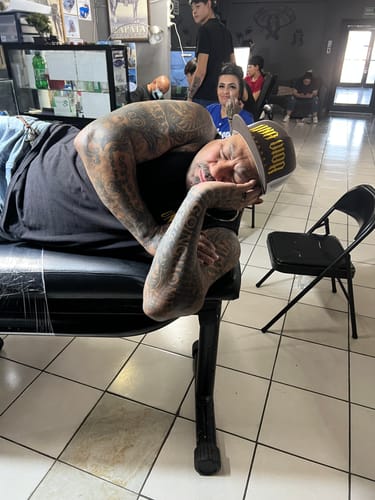 Customer rests comfortably on a tattoo bench, showing the pain-free experience from the Painless Tattoo cream.