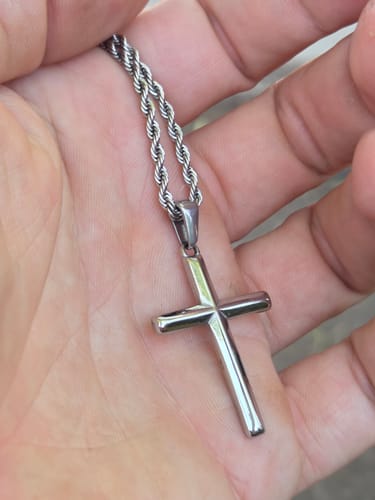 Cliente sosteniendo el brillante colgante Crucifix en la palma de su mano.