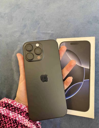 Cliente sosteniendo un iPhone 16 Pro Max negro nuevo en la mano, junto a su caja original.